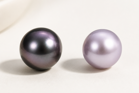 Purple Tahitian pearl beside a lavender freshwater pearl showing the difference between dark overtone and soft body color.
