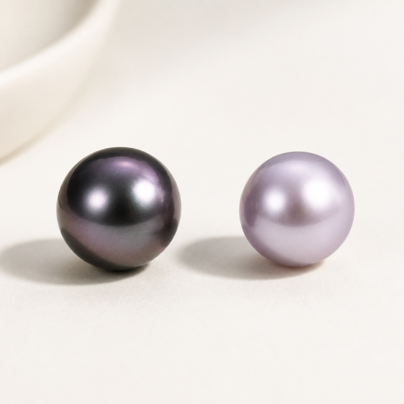 Purple Tahitian pearl beside a lavender freshwater pearl showing the difference between dark overtone and soft body color.