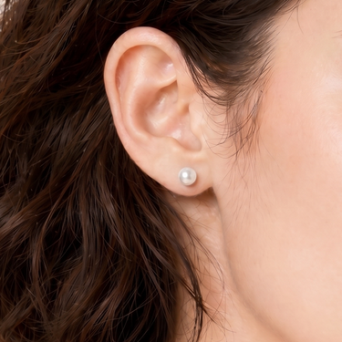 5.5–6.0mm White Akoya Pearl Stud Earrings shown in a close-up ear view, featuring a petite round pearl with bright luster.