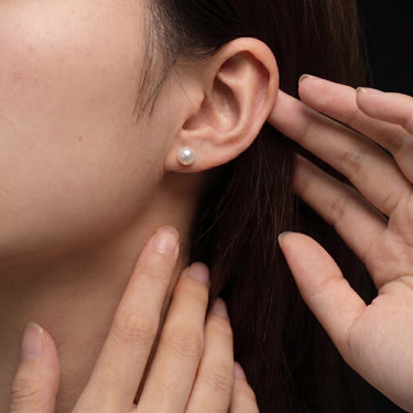 6.0–6.5mm White Akoya Pearl Stud Earrings shown in a close-up ear view, featuring a round pearl with bright luster.