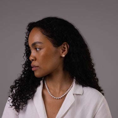 Model wearing 10mm peach freshwater pearl stud earrings