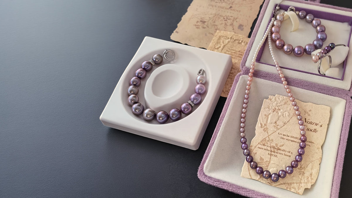 Naturally colored purple pearl jewelry arranged in lavender boxes and a white display tray